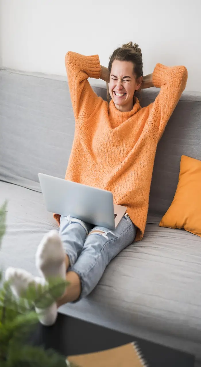 women is working online on her laptop comfortably and smiling